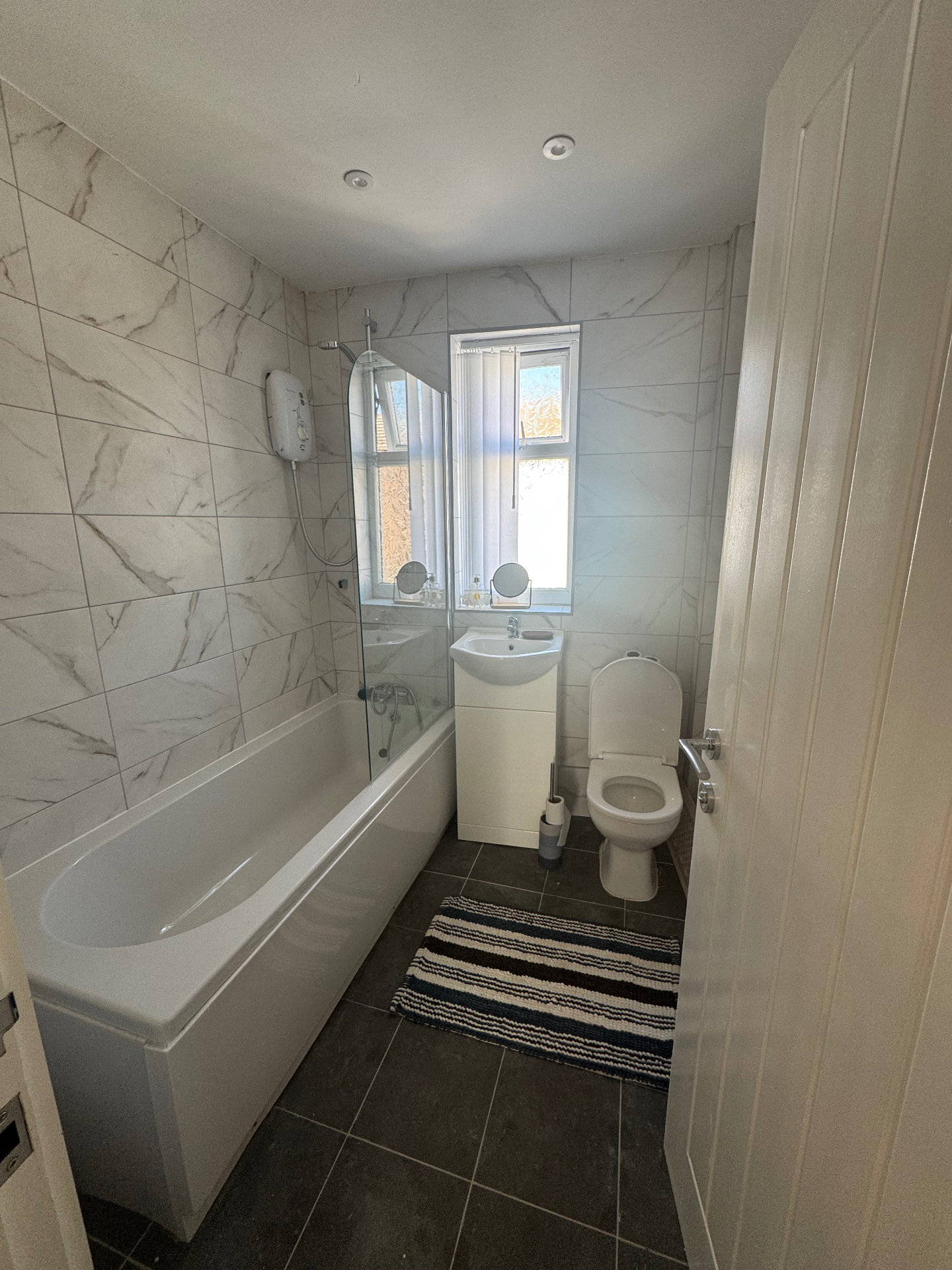 A clean, modern family bathroom with a bath and shower, washbasin and toilet
